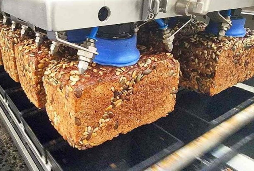 Dette billede illustrere Gribesystem til automatisk panering af friske rugbrøds skiver