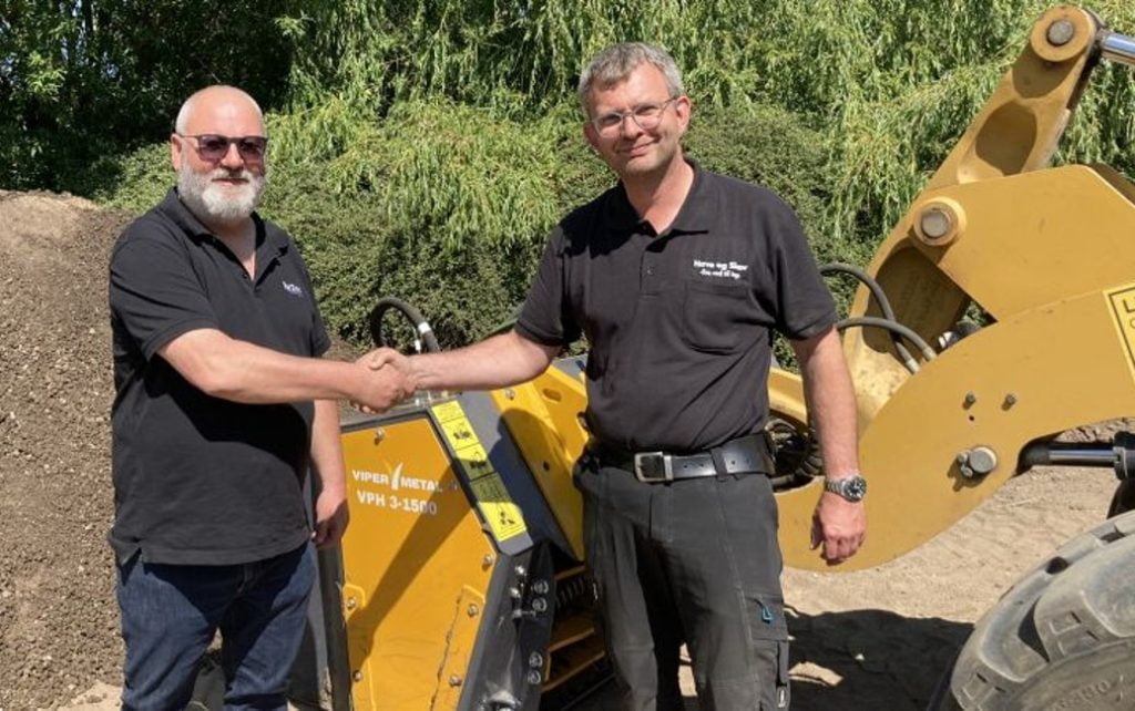 Foto: Fra venstre til højre: Salgskonsulent Peter Ry Schmidt (ReTec) og Uffe Klinkby (Have og Skov) står foran ViperMetal sorteringsskovlen og giver hinanden hånd på handlen.