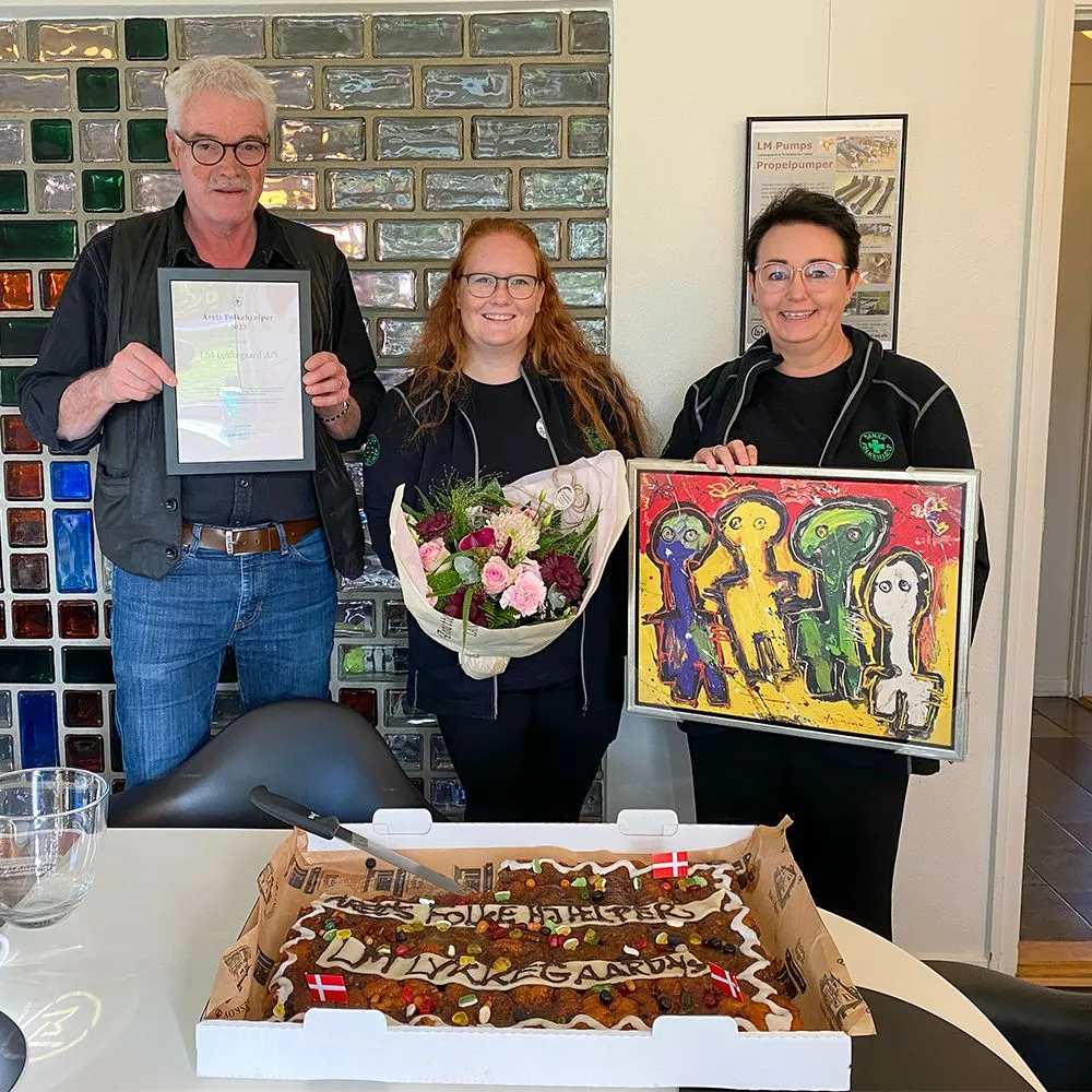 Karsten Lykkegaard sammen med Pia og Lonnie fra Dansk Folkehjælp med diplom og maleriet